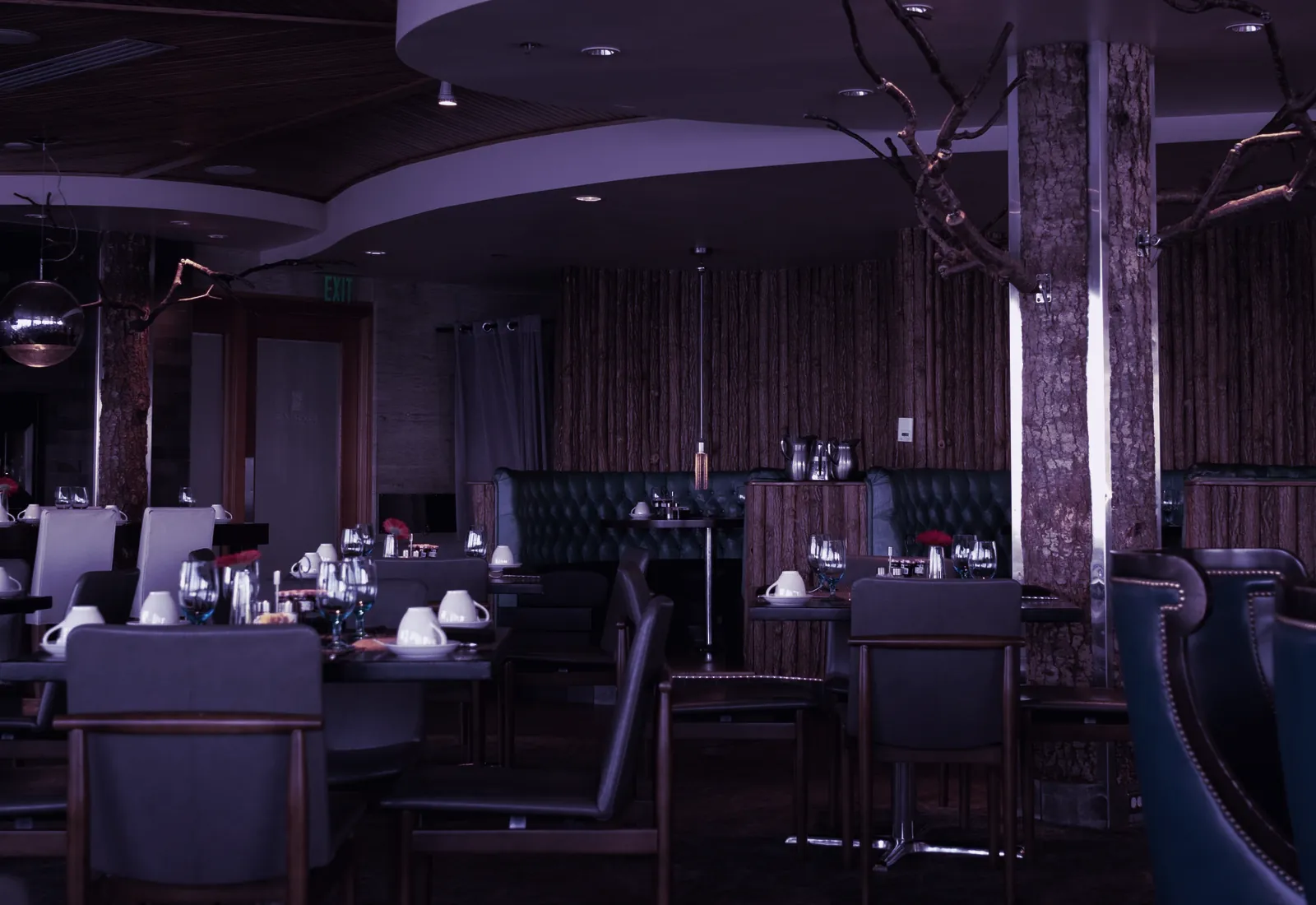 Enterijer restorana sa toplim osvetljenjem i postavljenim stolovima