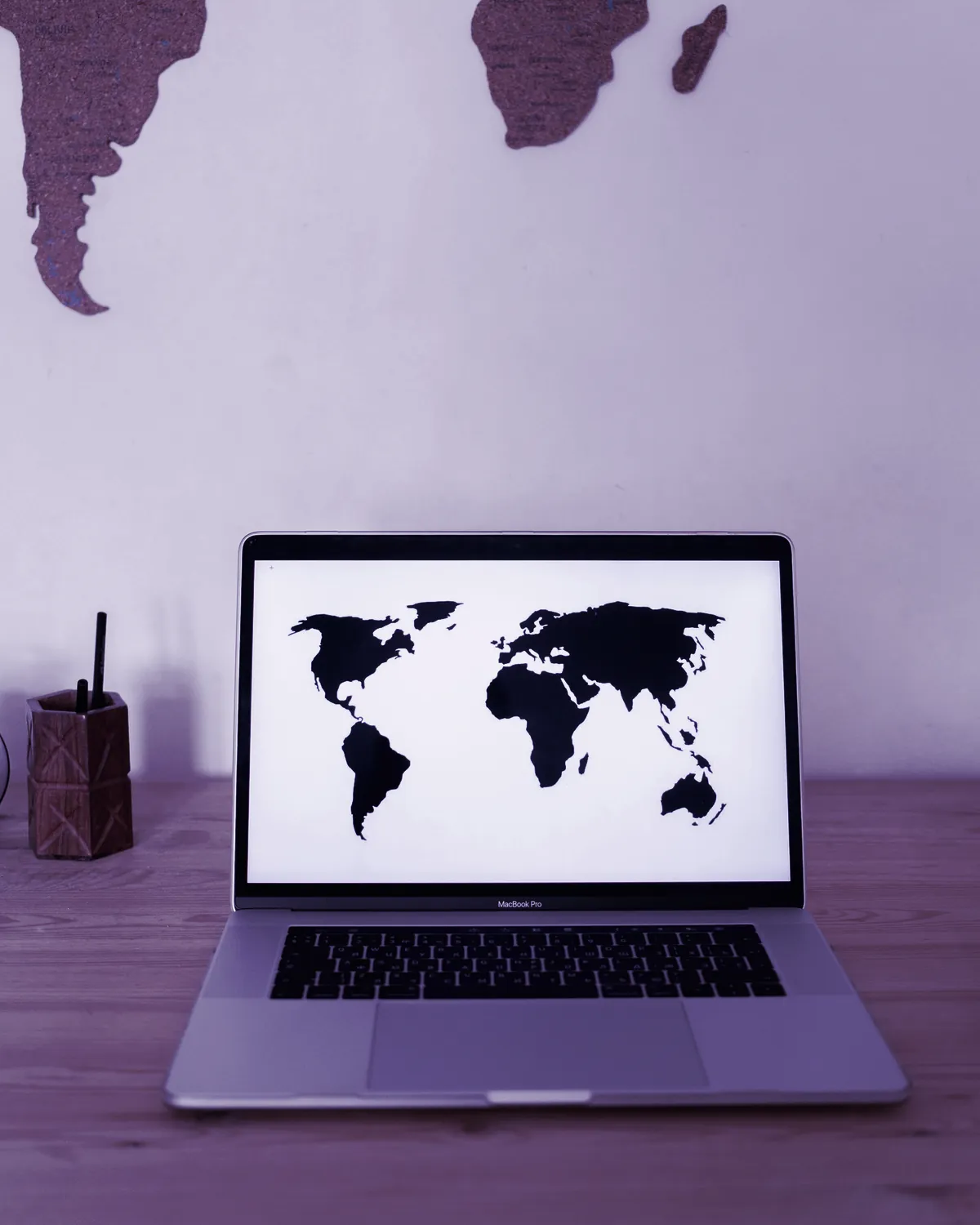 Laptop sa mapom sveta na ekranu na drvenom stolu, simbol globalne ponude za male agencije